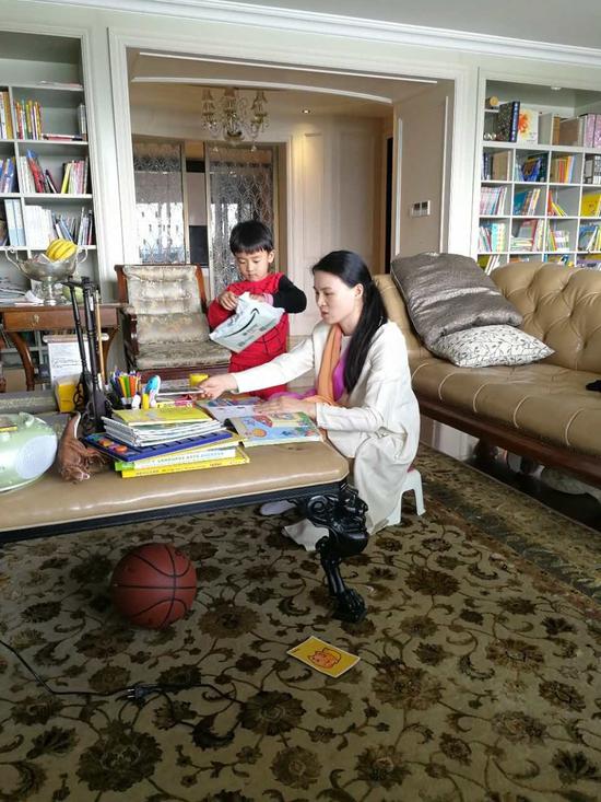 朱小贞和小儿子在客厅里，背后书架为起火点。受访者供图