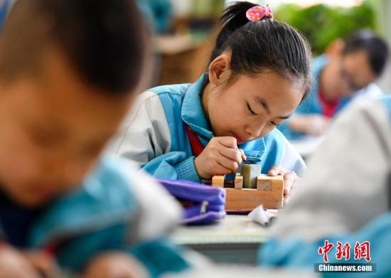 资料图:学生在专业老师的指导下练习篆刻艺术。中新社记者 刘新 摄